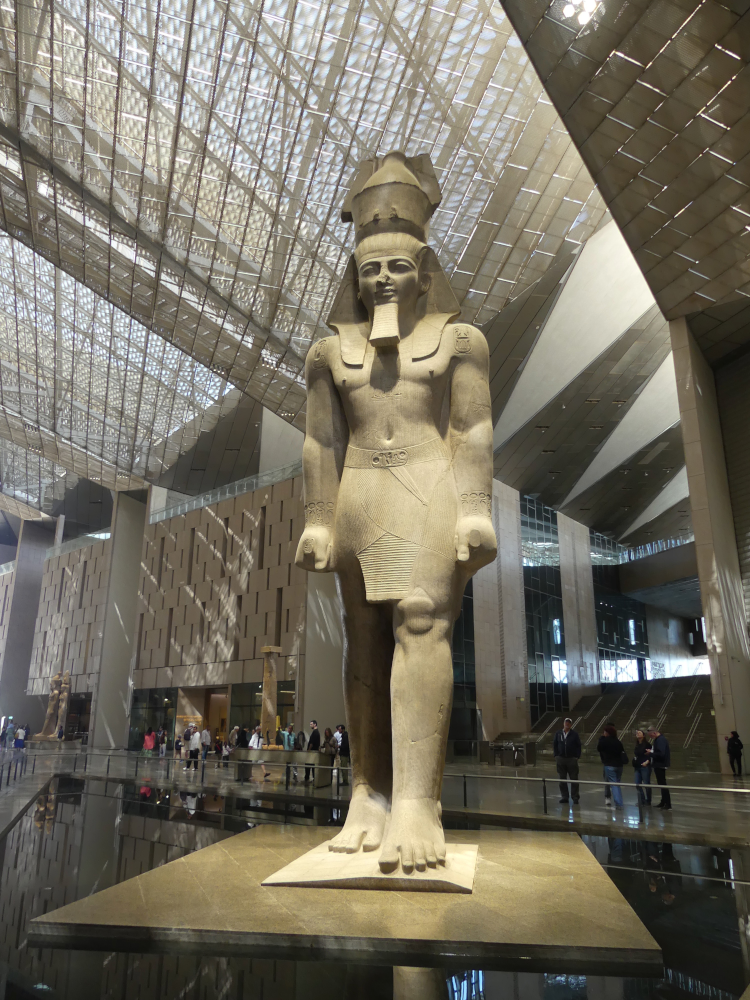 Ramsès II (XIIIe siècle av. J.-C.) dans le Grand Hall Grand Egyptian Museum, 2026 ; agrandissement : Vue du Grand Hall et de la statue de Ramsès II depuis le 3e étage du Grand Egyptian Museum, photos. I. Grégor.