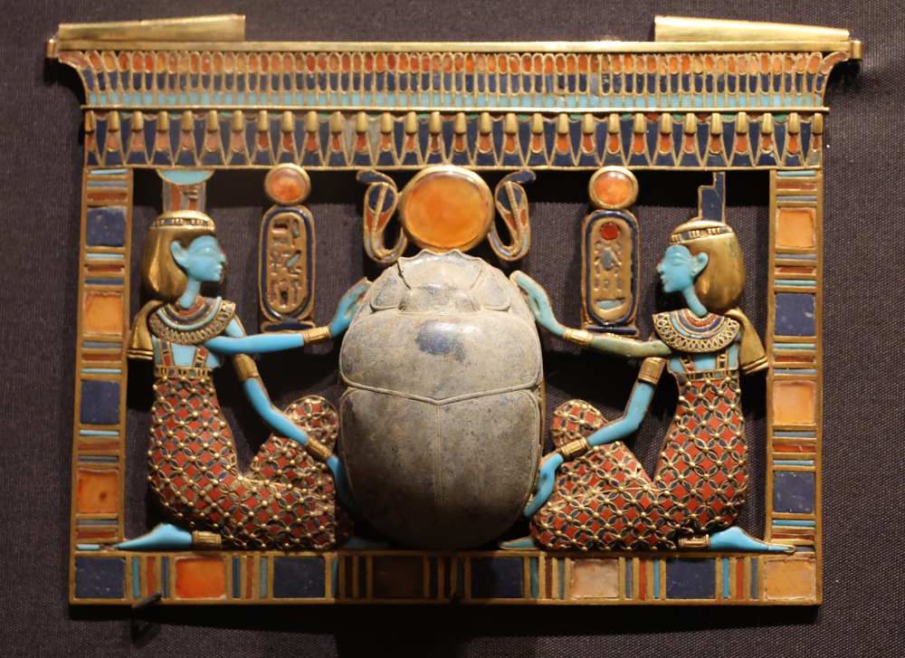 Pendentif de Toutânkhamon, Grand Egyptian Museum, photo. G. Grégor. ; agrandissement : amulettes et statuettes retrouvées dans le tombeau de Toutânkhamon (XIVe siècle avant J.-C.), Grand Egyptian Museum, photo. I. Grégor.