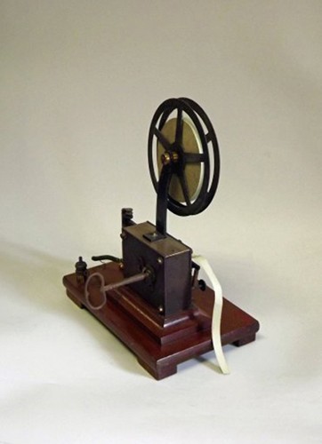Le télégraphe électrique. Une pile est reliée à un électroaimant (à gauche) par le biais d?un interrupteur (à droite). L?action sur l?interrupteur abaisse un poinçon sur le ruban, ce qui permet de retranscrire un code binaire de type Morse. En pratique, l?interrupteur peut être situé à des milliers de kilomètres.