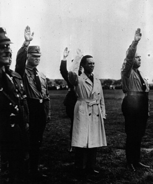 De gauche &agrave; droite : Goebbels (avec l'imperm&eacute;able) et M. G. Strasser saluant le drapeau, 1902, Paris, BnF.
